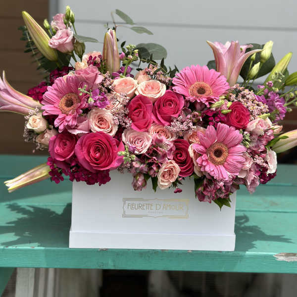 Pink roses and gerbera daisies arranged in a white box