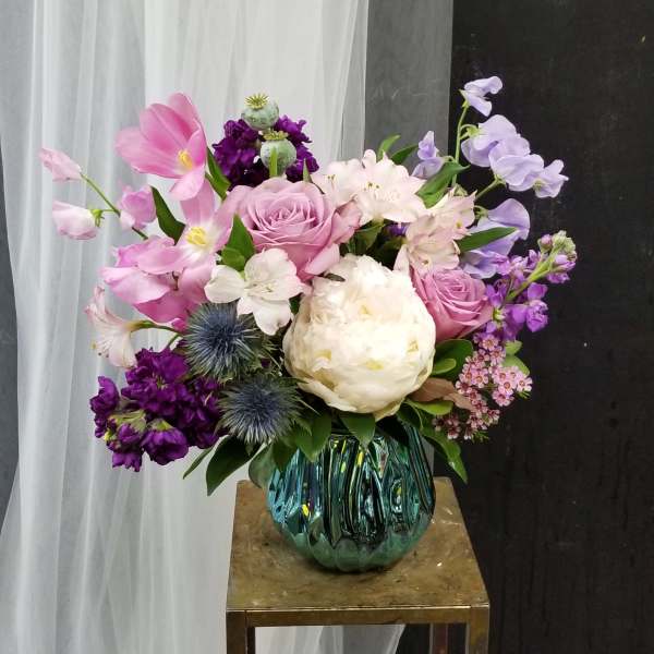 Pink and white floral arrangement in a blue glass vase