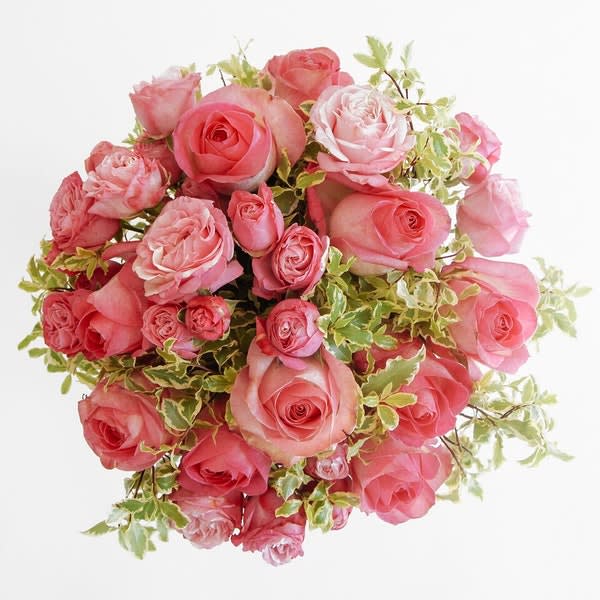 Tight round bouquet of pink roses and spray roses with variegated foliage