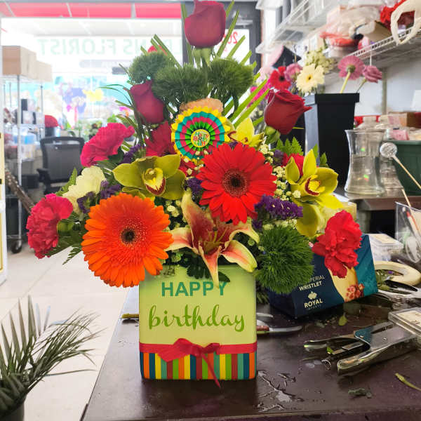 Colorful birthday flower arrangement with gerbera daisies and roses in a gift box