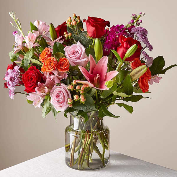 Mixed bouquet of roses, lilies, and alstroemeria in a glass vase