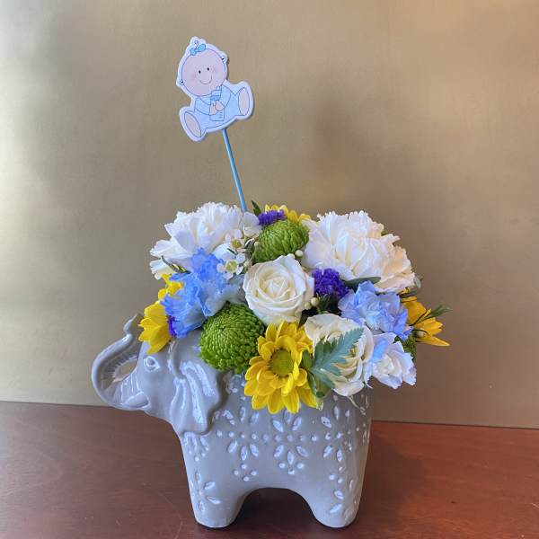 Flower arrangement in a gray elephant planter with a baby topper