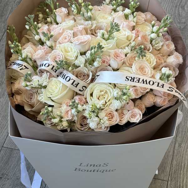 Large bouquet of pale pink and cream roses with white blooms in a box