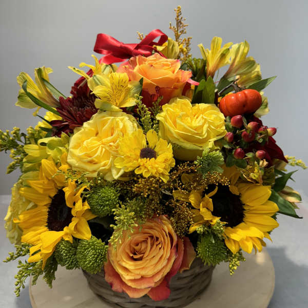 Basket arrangement with yellow roses, sunflowers, and orange blooms