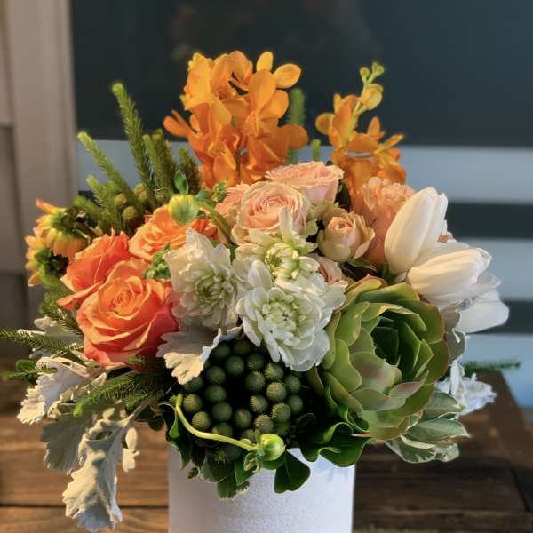 Orange and white floral arrangement in a white vase