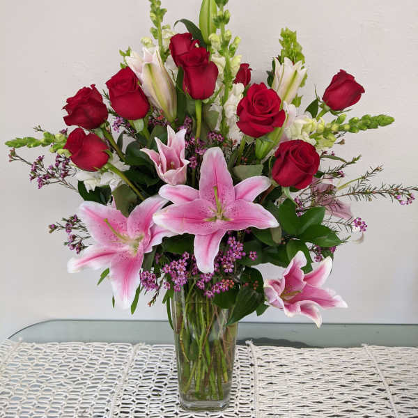 Bouquet of pink lilies and red roses in a clear glass vase