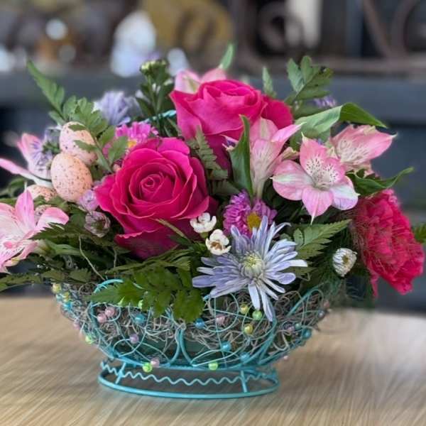 Pink roses and mixed flowers in a decorative wire basket