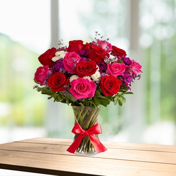 Bouquet of red and pink roses in a clear glass vase with a red ribbon