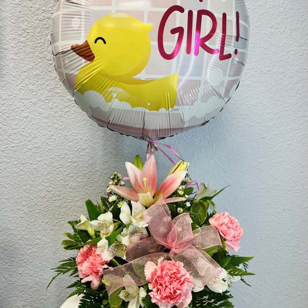 Pink and white flower arrangement with a duck-shaped balloon reading "it's a GIRL!"