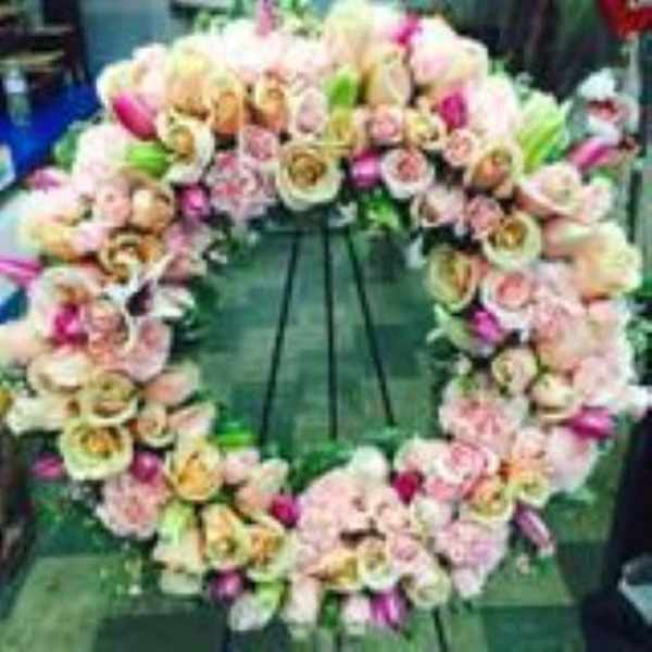 Standing wreath of peach and pink flowers on a metal easel