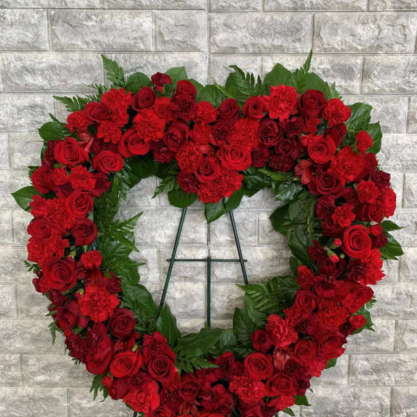 Heart-shaped red floral wreath on a stand