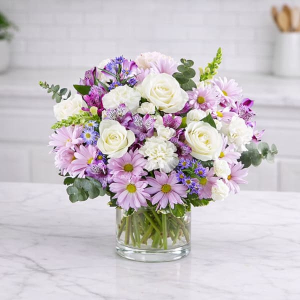 Bouquet of white roses and pink daisies in a clear glass vase
