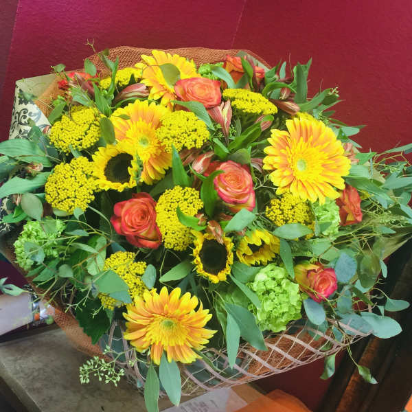 Mixed bouquet of yellow gerberas, coral roses, and green filler flowers