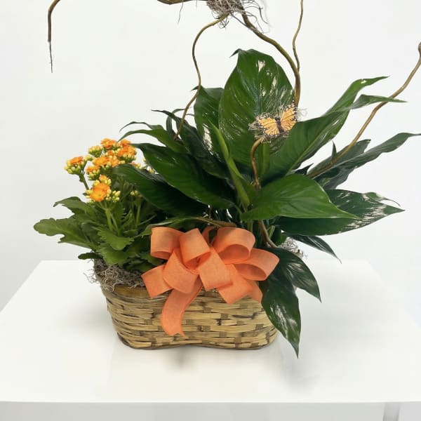 Basket garden with green plants, orange flowers, curly branches, and a decorative bird and bow.