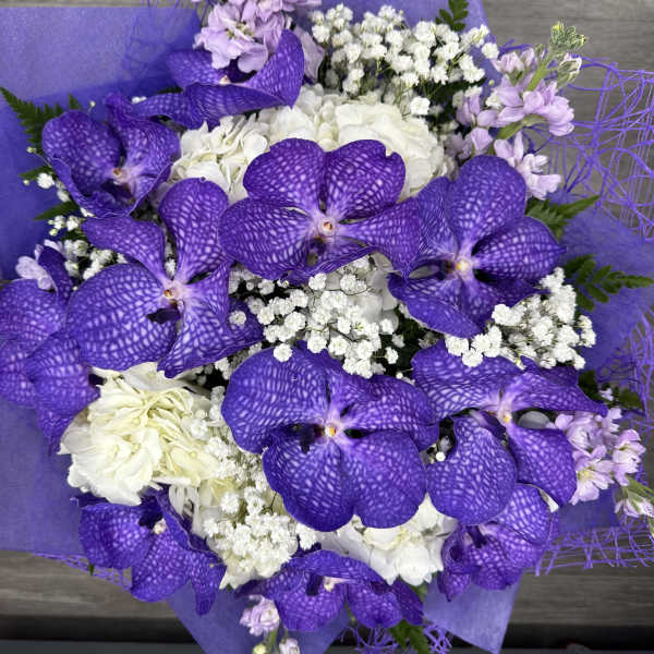 Purple orchid bouquet with white filler flowers and wrapped paper