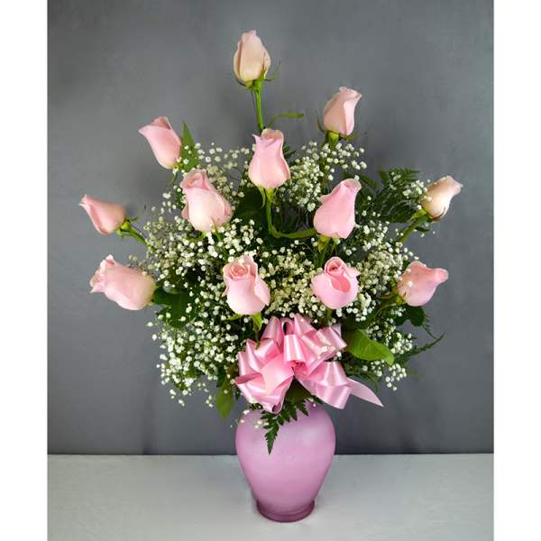 Pink roses arranged in a pink vase with a ribbon bow