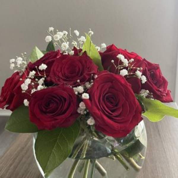 Red roses in a clear glass vase with white baby's breath