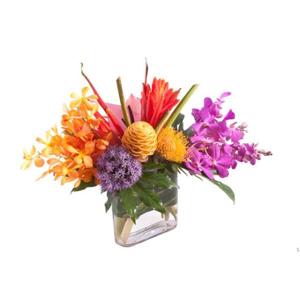 Colorful tropical flower arrangement in a clear rectangular vase