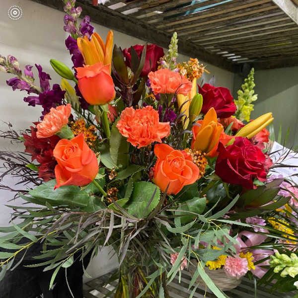 Bright mixed bouquet of roses, lilies, and carnations in a glass vase