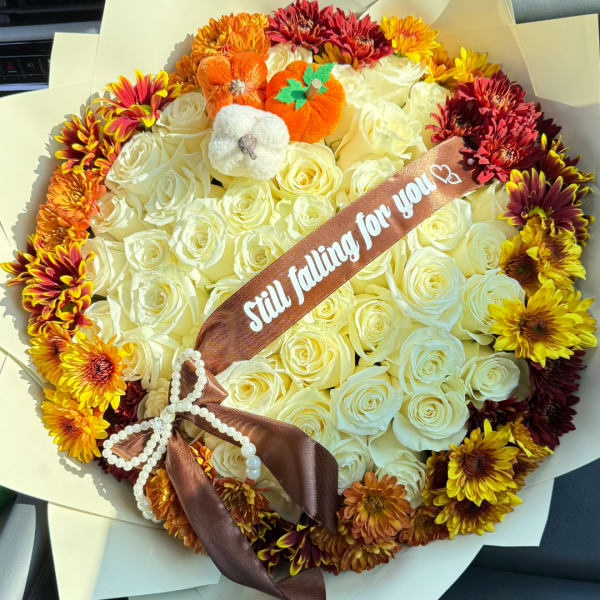 Round bouquet of white roses with autumn-colored chrysanthemums and a brown ribbon.