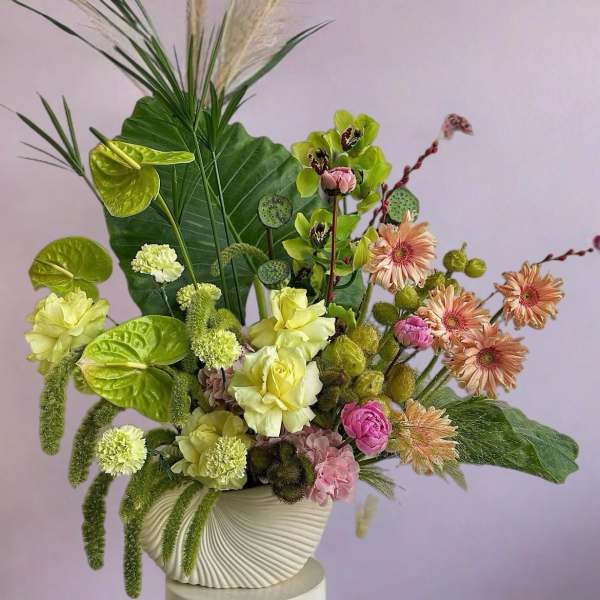 Mixed floral arrangement in a white textured vase with pink and green blooms