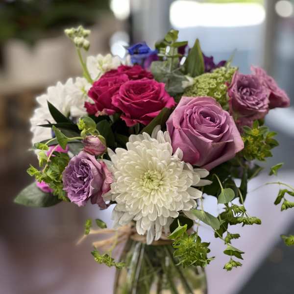 Bouquet of pink and purple roses with white chrysanthemum in a glass vase