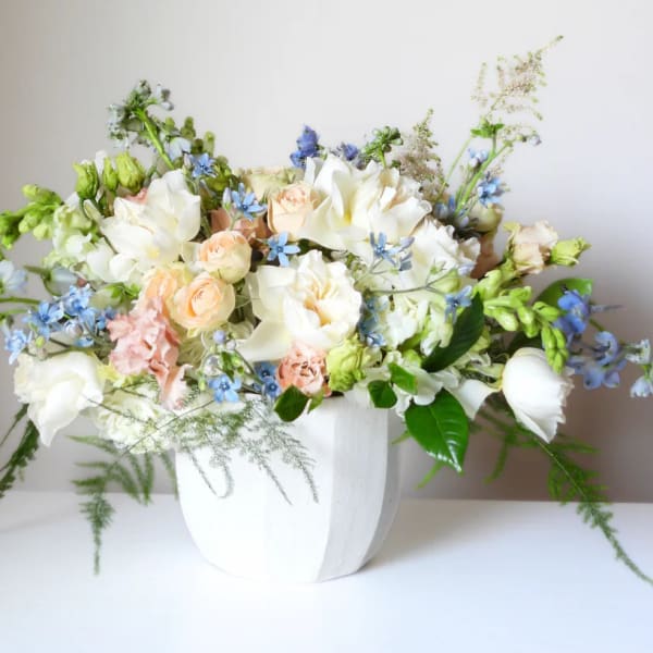 White and peach floral arrangement in a white vase