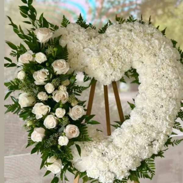 Heart-shaped white floral wreath on a wooden easel