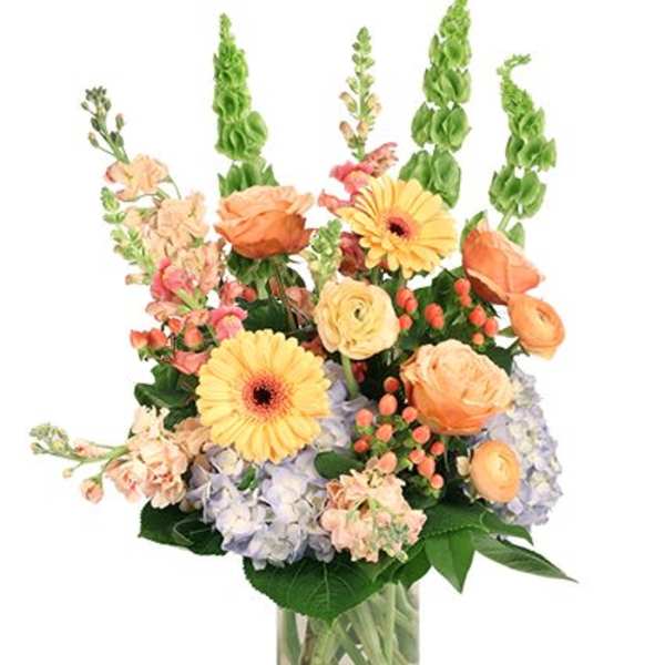Mixed bouquet of peach and yellow flowers in a clear glass vase