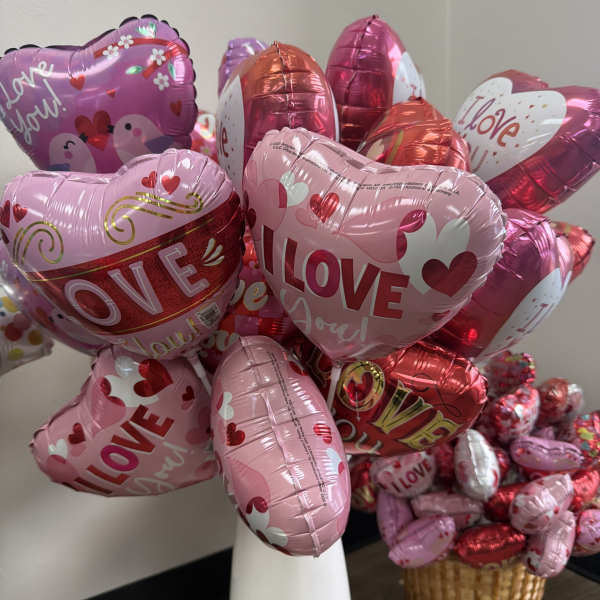 Heart-shaped pink and red balloons with love messages in a white vase and basket