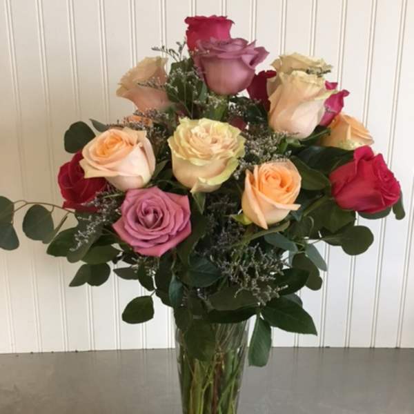 Mixed roses in a clear glass vase with greenery