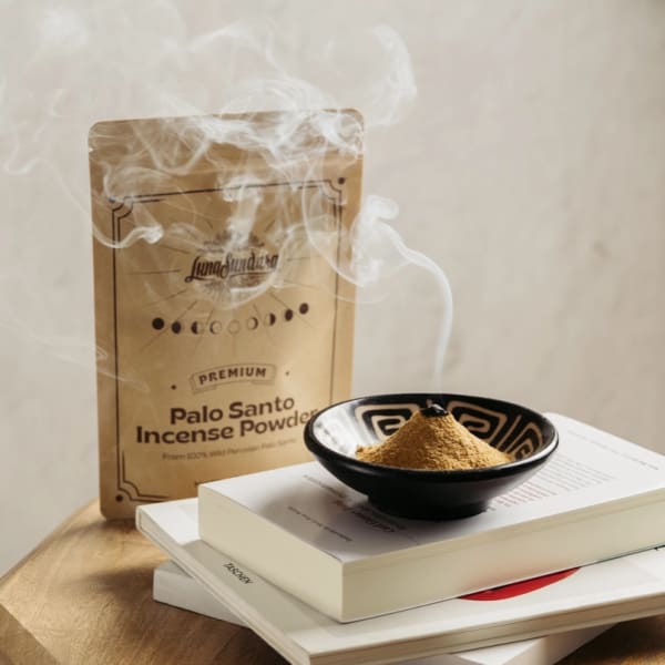 Palo Santo incense powder in a bowl with smoke rising beside a package