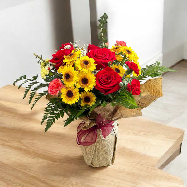 Bouquet of red roses and yellow daisies wrapped in paper