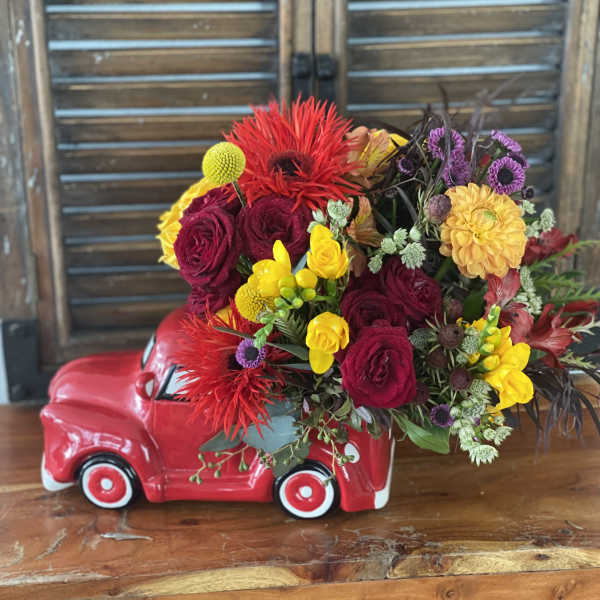 Colorful flower arrangement in a red ceramic truck container