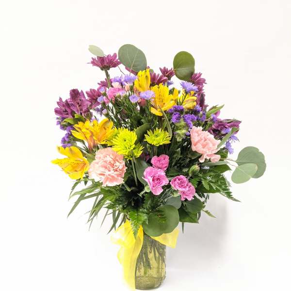 Mixed bouquet of yellow, pink, and purple flowers in a glass vase