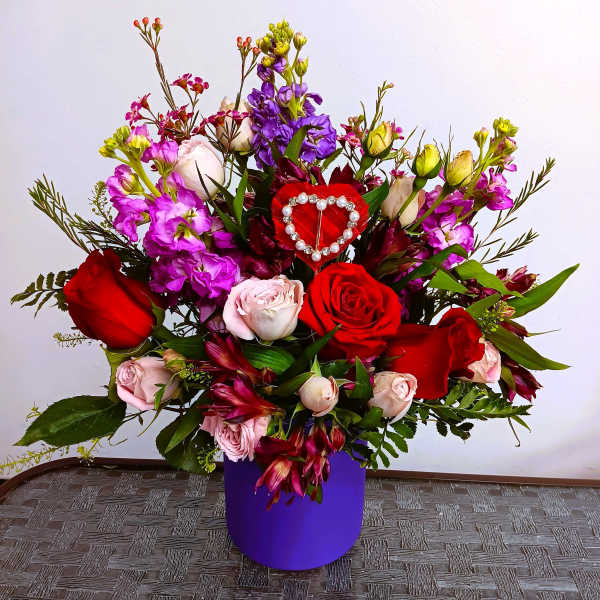 Bouquet of red and pink roses with purple flowers in a purple box