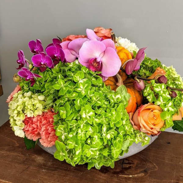 Mixed floral arrangement with orchids, roses, and hydrangeas in a low bowl