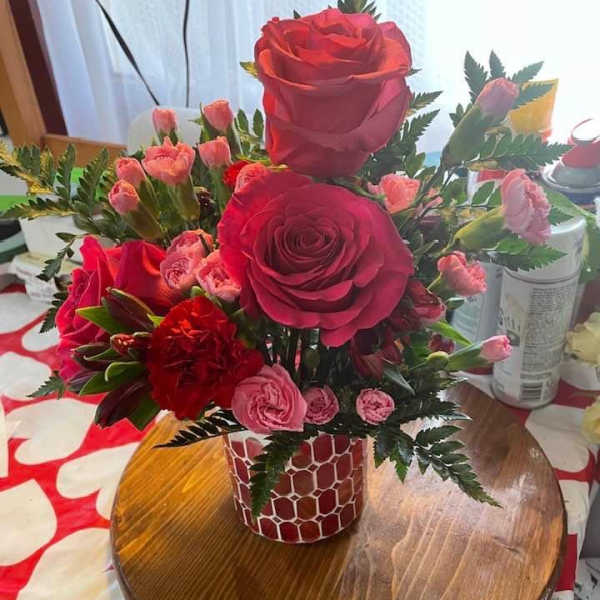 Red and pink rose bouquet in a patterned vase