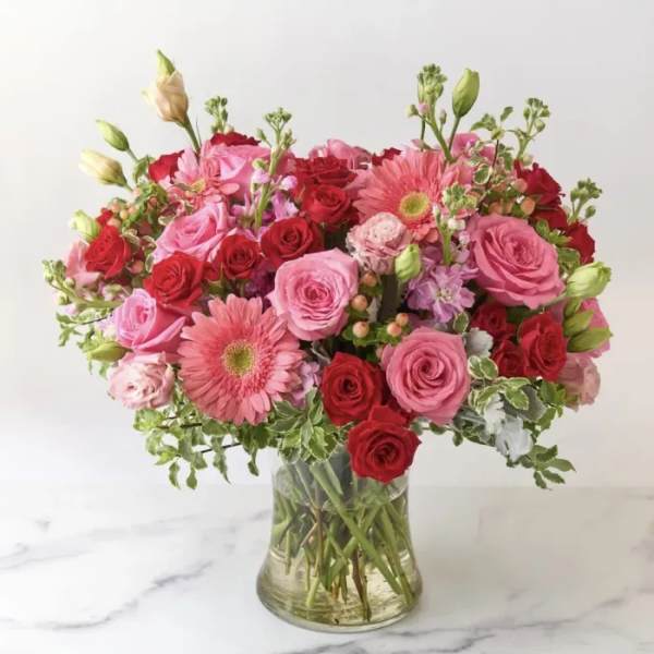 Pink and red rose bouquet with gerbera daisies in a clear glass vase
