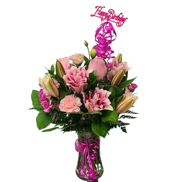 Pink bouquet with lilies and carnations in a glass vase, topped with a birthday sign