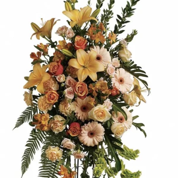 Tall standing floral spray with yellow lilies, peach roses, and pale gerberas