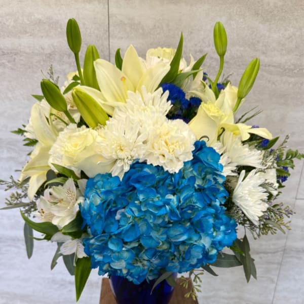 Blue hydrangeas and white lilies in a cobalt vase