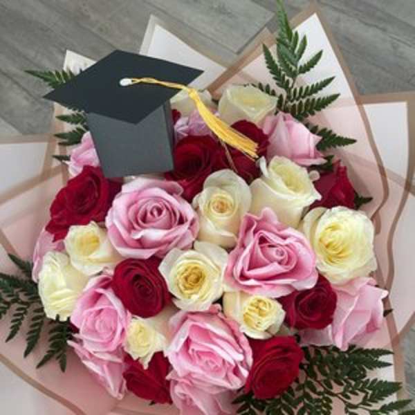 Bouquet of pink, red, and white roses with a graduation cap topper