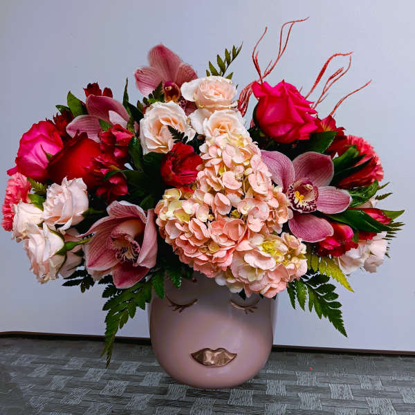 Pink and red mixed flower arrangement in a blush vase