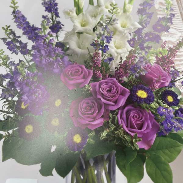 Bouquet of purple roses and white gladiolus in a glass vase