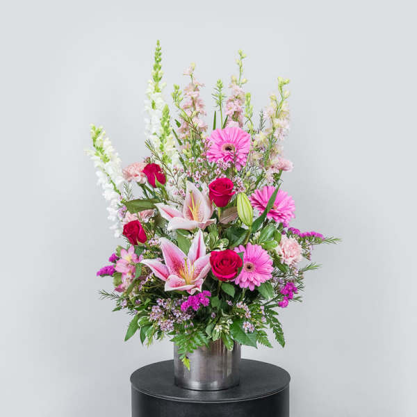 Tall mixed bouquet with pink lilies, roses, and gerbera daisies in a metal vase