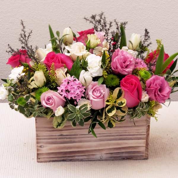 Mixed pink and white flower arrangement in a wooden box