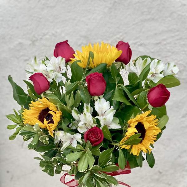 Bouquet of red roses, sunflowers, and white alstroemeria in a glass vase