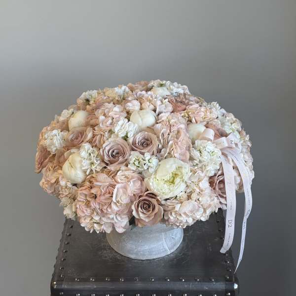 Round bouquet of blush and white flowers in a silver vase