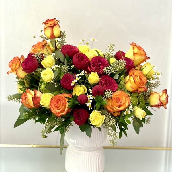 Bouquet of red, yellow, and orange roses in a white vase